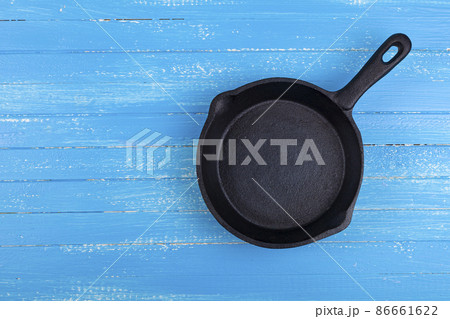 Empty cast iron pan on a blue wooden background. Empty cast iron pan on a blue wooden background. 86661622