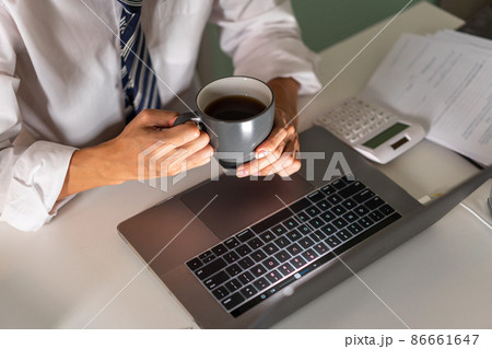 Overwork Concept An office man who works late drinking a cup of coffee while concentrating on his work on the notebook 86661647