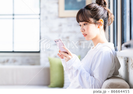 リビングでスマホを見る若い女性 リビングでスマホを見る若い女性 86664455
