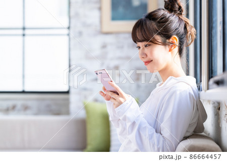 リビングでスマホを見る若い女性 86664457