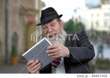 Senior caucasian man in formal wear immersed into gaming. Senior caucasian man in formal wear immersed into gaming. 86667408