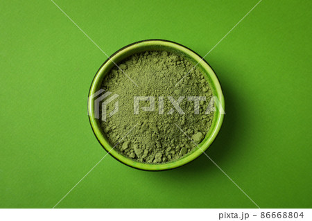 Bowl of matcha powder on green background 86668804