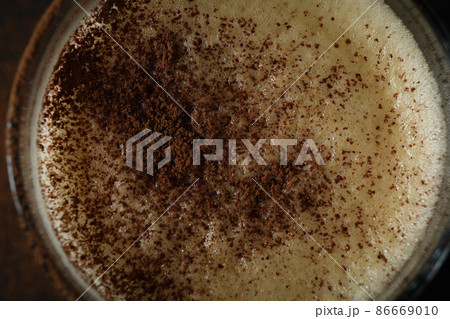 Glass of coffee with foam and cocoa powder, close up 86669010