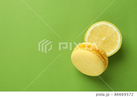 Yellow macaroon and lemon on green background Yellow macaroon and lemon on green background 86669372