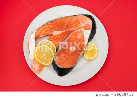 raw fresh salmon on ceramic plate on red raw fresh salmon on ceramic plate on red 86669418