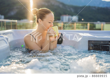 Portrait of young carefree happy smiling woman relaxing at hot tub during enjoying happy traveling moment vacation life against the background of green big mountains Portrait of young carefree happy smiling woman relaxing at hot tub during enjoying happy traveling moment vacation life against the background of green big mountains 86669935