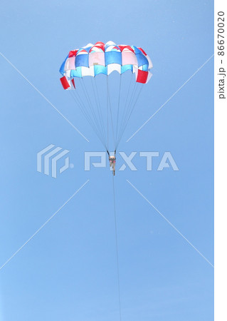 A woman is gliding using a parachute on the background of cloudy blue sky. 86670020