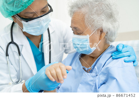 Doctor help Asian senior or elderly old lady woman patient wearing a face mask in hospital for protect safety infection and kill Covid-19 Coronavirus. 86671452