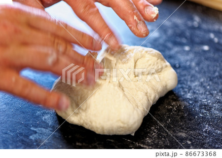 Close-up view of professional baker preparing bread dough in a kitchen Close-up view of professional baker preparing bread dough in a kitchen 86673368