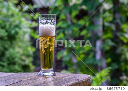 glass with beer on the table against the backdrop of greenery. 86673710