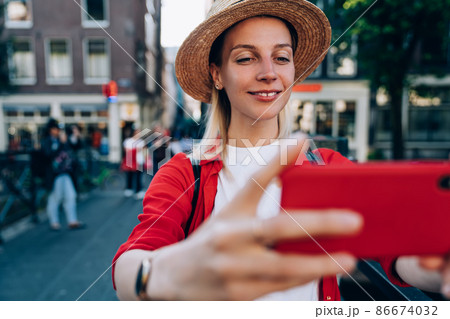 Smiling woman taking selfie on smartphone on city street 86674032