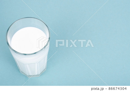 Glass of fresh white milk on blue background. Studio Photo Glass of fresh white milk on blue background. Studio Photo 86674304