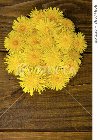 Fresh yellow dandelions in wooden bowl, top view. Fresh yellow dandelions in wooden bowl, top view. 86674606