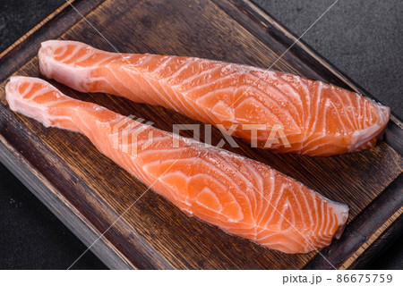 Fresh salmon fillets on black cutting board with herbs and spices 86675759