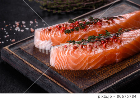 Fresh salmon fillets on black cutting board with herbs and spices Fresh salmon fillets on black cutting board with herbs and spices 86675784