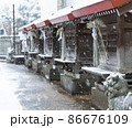 雪が降る日の神社 並ぶ祠 風雪に揺れる社の鈴緒（すずお） 86676109
