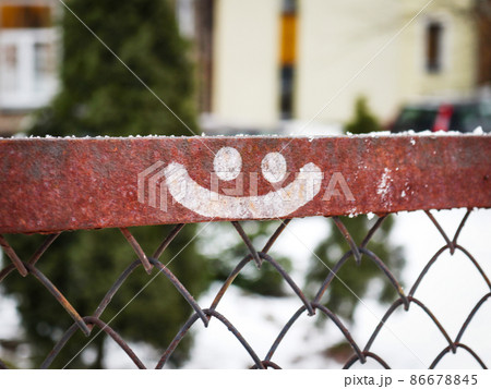 Smiley face drawn on metal fence on winter yard background 86678845