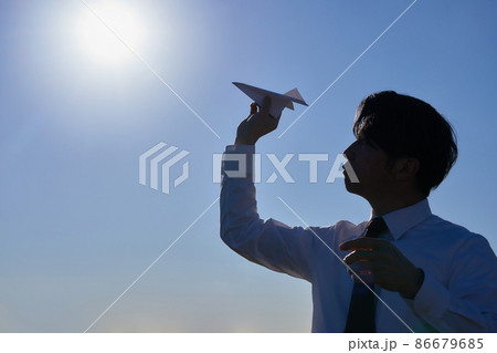 紙飛行機を飛ばす男性のシルエット 86679685