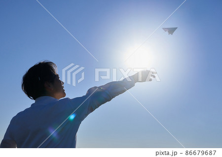 紙飛行機を飛ばす男性のシルエット 86679687
