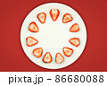 Top view of half strawberry in a plate on isolated red background. 86680088