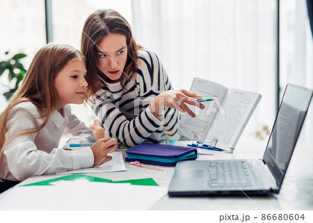 Mother and daughter watching a textbook together. Mother and daughter watching a textbook together. 86680604