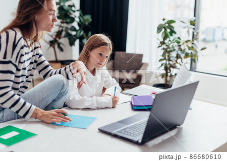 Girl does her homework her mother sits next to her Girl does her homework her mother sits next to her 86680610