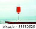 水色の風景に溶け込む赤いシャンペングラスとコピースペース 86680625