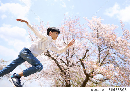 桜の木の前でダッシュする小学生の男の子 86683363