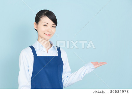 手で案内するエプロンの女性 86684978