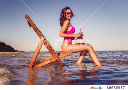 Happy young sexy woman in pink bikini posing with coctail on lounger beach. summer vacation concept 86686937