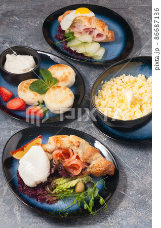 cheesecakes, porridge, croissants with salmon and ham on a gray background. Concept cheesecakes, porridge, croissants with salmon and ham on a gray background. Concept 86687136