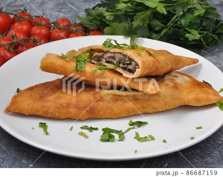 cheburek with beef and greens on a white plate cheburek with beef and greens on a white plate 86687159