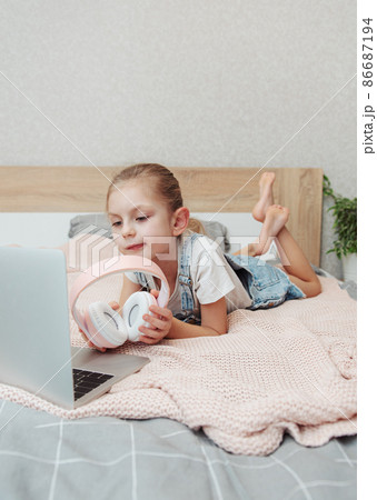 Little girl learning online with laptop computer at bedroom. 86687194