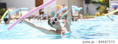 Young woman is engaged in aqua aerobics in pool closeup Young woman is engaged in aqua aerobics in pool closeup 86687555