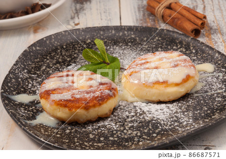 cheesecakes with condensed milk and a mint leaf on a dark plate cheesecakes with condensed milk and a mint leaf on a dark plate 86687571