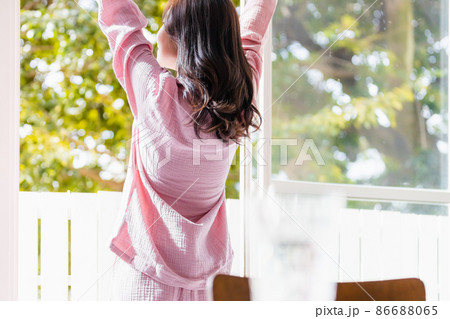 窓際に立って朝の光を浴びる気分爽快な女性 86688065