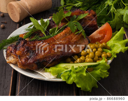 pork ribs on coals on a plate served with greens 86688960
