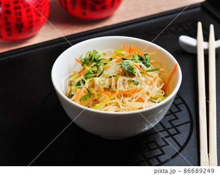 cellophane with vegetables in a white bowl and a black background cellophane with vegetables in a white bowl and a black background 86689249