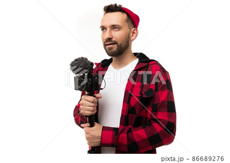 blogger in a half-turn with a camera and a microphone in his hands on a white background blogger in a half-turn with a camera and a microphone in his hands on a white background 86689276