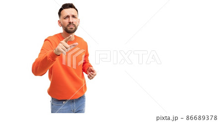 a man on a white background in an orange sweater points his finger forward choosing someone or 86689378