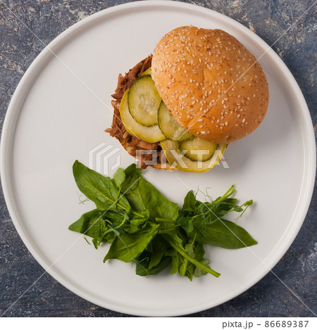 Burger with boiled beef, zucchini and pickle. Top view 86689387