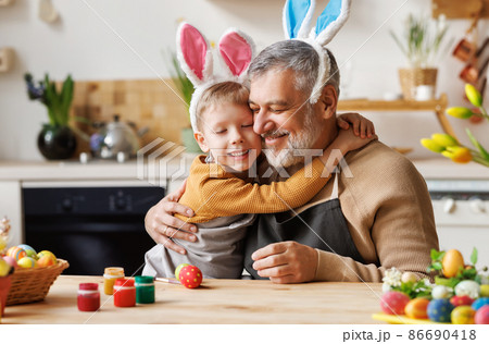 Happy family loving grandfather and cute little boy grandson embracing while painting Easter eggs 86690418