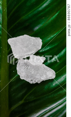Crystal clear alum cubes or Potassium alum on green leaf. Chemical compound substance. Concept for beauty , spa and underarm treatment industrial.  86690787