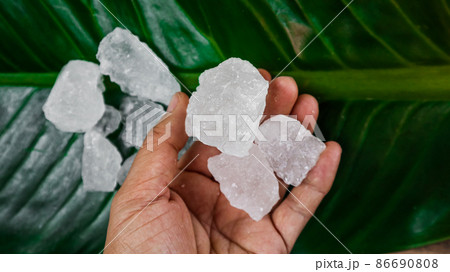 Crystal clear alum cubes or Potassium alum on green leaf. Chemical compound substance. Concept for beauty , spa and underarm treatment industrial.  86690808