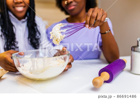 a couple of multiracial women cook sweet cake and have fun together a couple of multiracial women cook sweet cake and have fun together 86691486