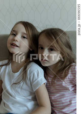 Two younger sisters are playing on the couch. Cozy home communication 86696595