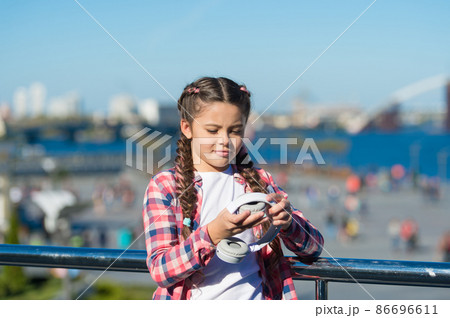 Girl little kid hold foldable headphones while walk  86696611