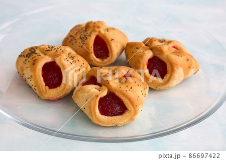 Homemade crunchy butter cookies envelopes with jam and poppy seeds on a transparent glass plate 86697422