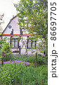 Pink country house with blooming saxifrage and juniper in the front garden. 86697705