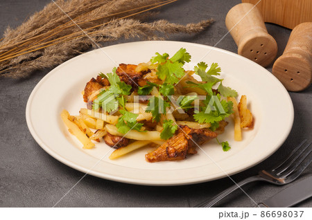 fried potatoes with chanterelles garnished with coriander 86698037